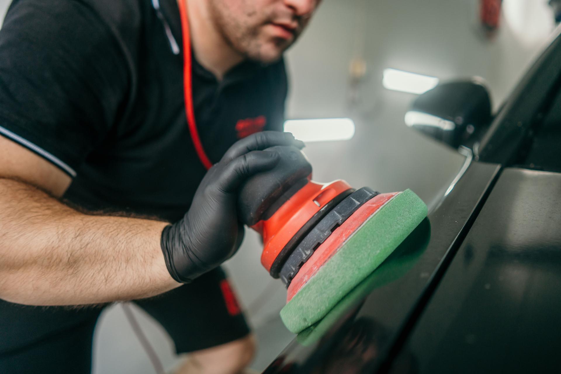 Car detailer polishing car in garage