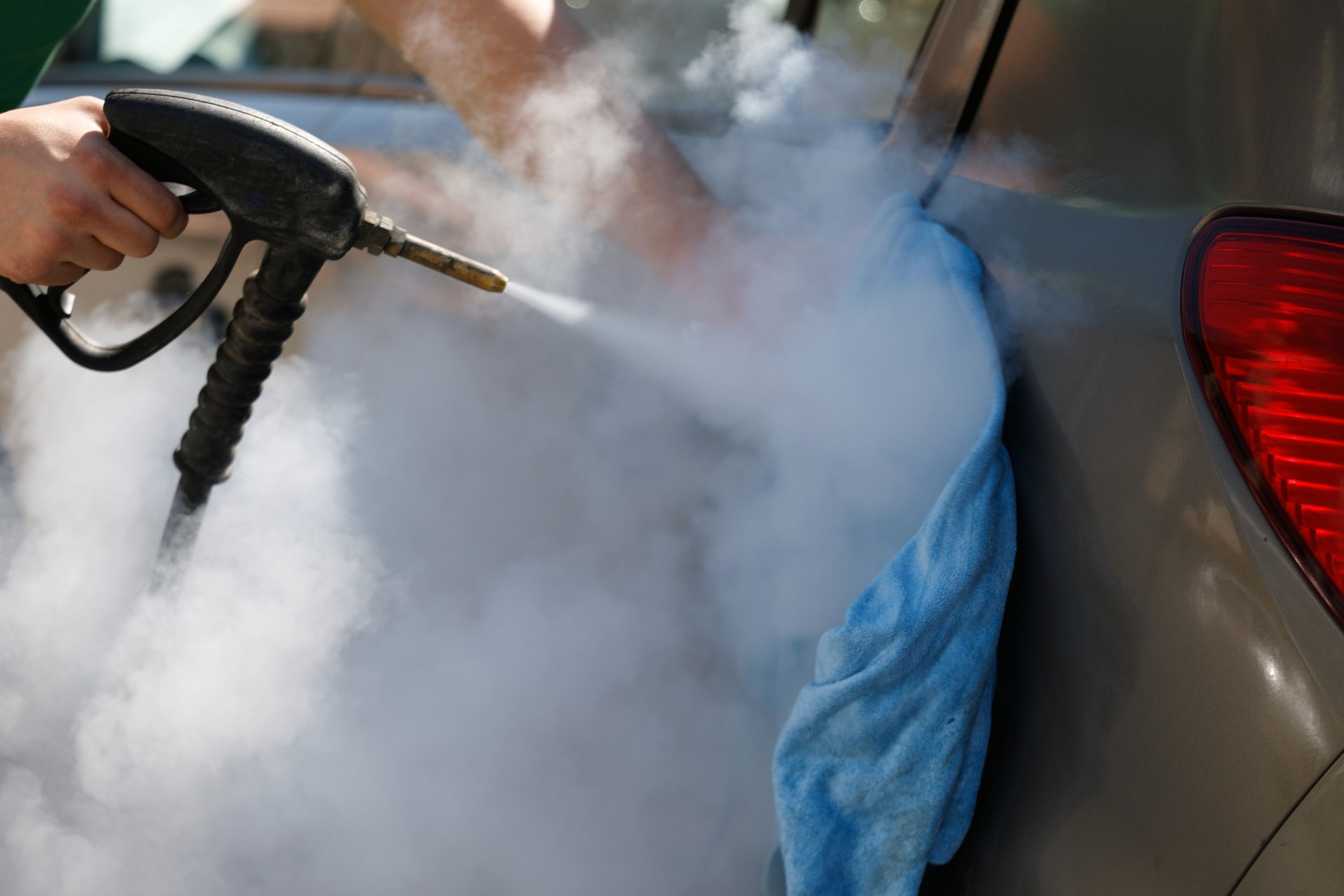 Car detailing. Car washing cleaning engine. Cleaning car using hot steam. Hot Steam engine washing. Soft lighting. Car wash man worker cleaning vehicle.